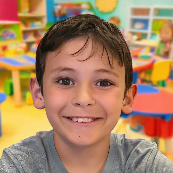 A cheerful boy smiles brightly, showcasing happiness in a colorful classroom setting.