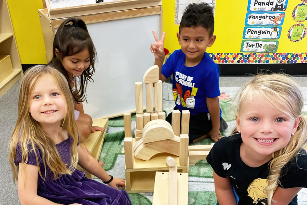 Children happily build with wooden blocks, showcasing creativity and teamwork in their colorful classroom.