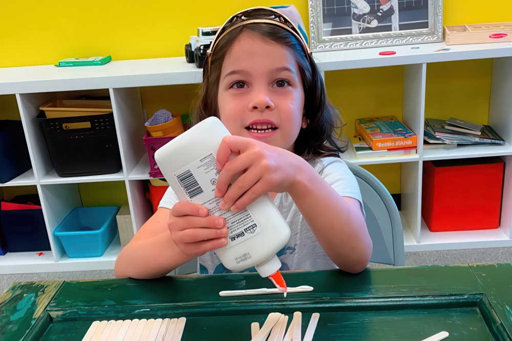 A child eagerly applies glue while working on an arts and crafts project.