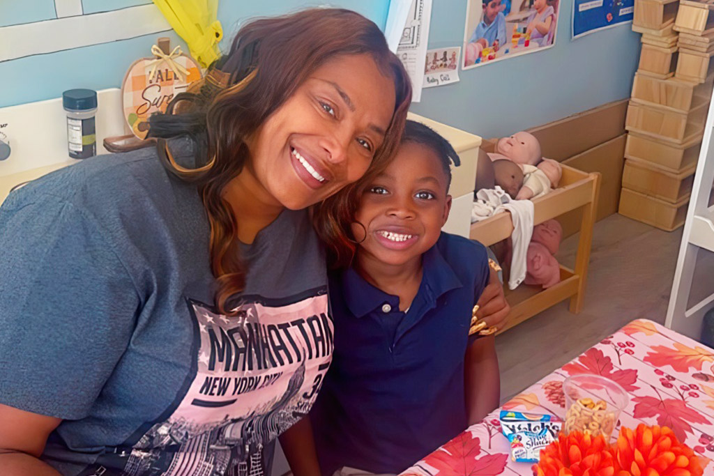 A teacher and a boy pose together a warm smile capturing a vibrant learning atmosphere.