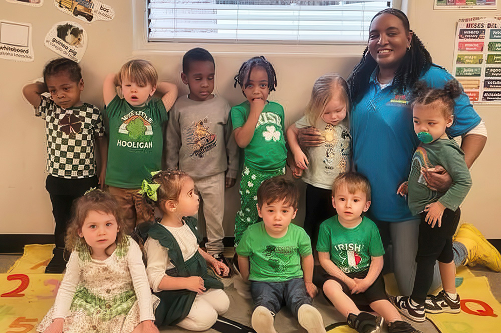 A teacher and her young students, display a moment of togetherness while celebrating St. Patrick's Day and donning green attire.