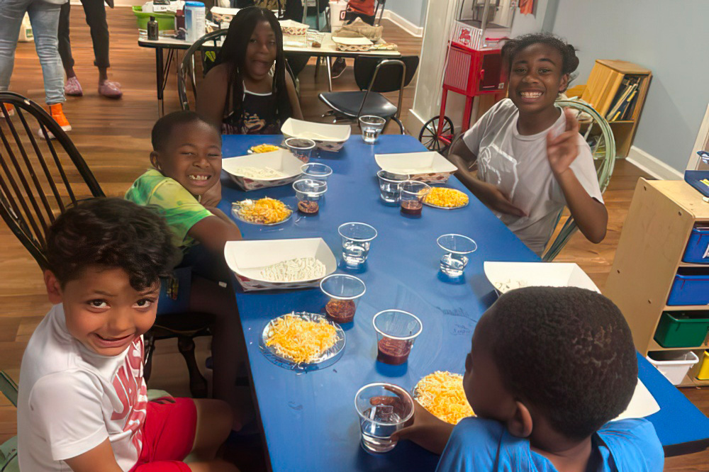 A cheerful group of kids poses together at a dining table, sharing a fun meal.