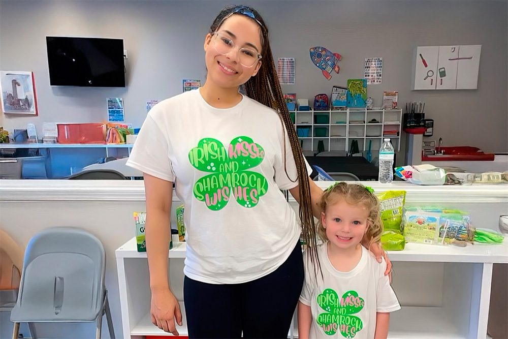 A teacher and a young girl posing happily in a brightly lit, welcoming space.