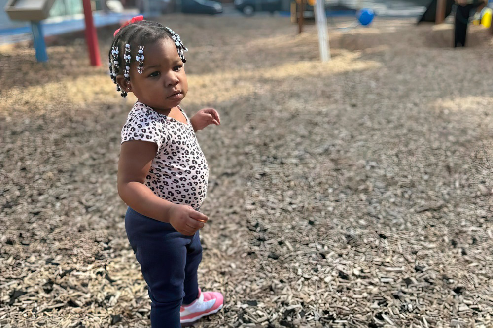 A young girl stands on a playground showing a sense of curiosity and confidence.