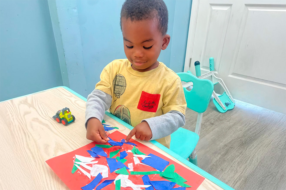 A boy carefully pieces together colorful shapes on a craft project, showcasing creativity and focus